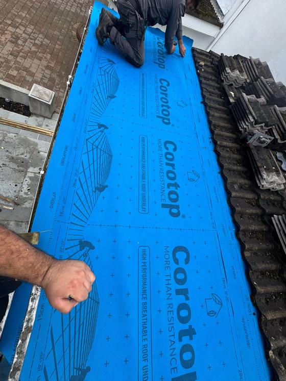 Roofer fitting membrane across a tiled roof