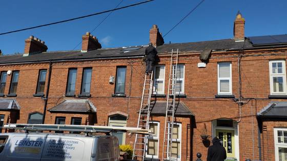Roofers working on a terraced street with ladders
